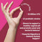 Hand holding a capsule with probiotic product information on a pink background