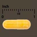 Yellow capsule pill next to an inch ruler on a dark background